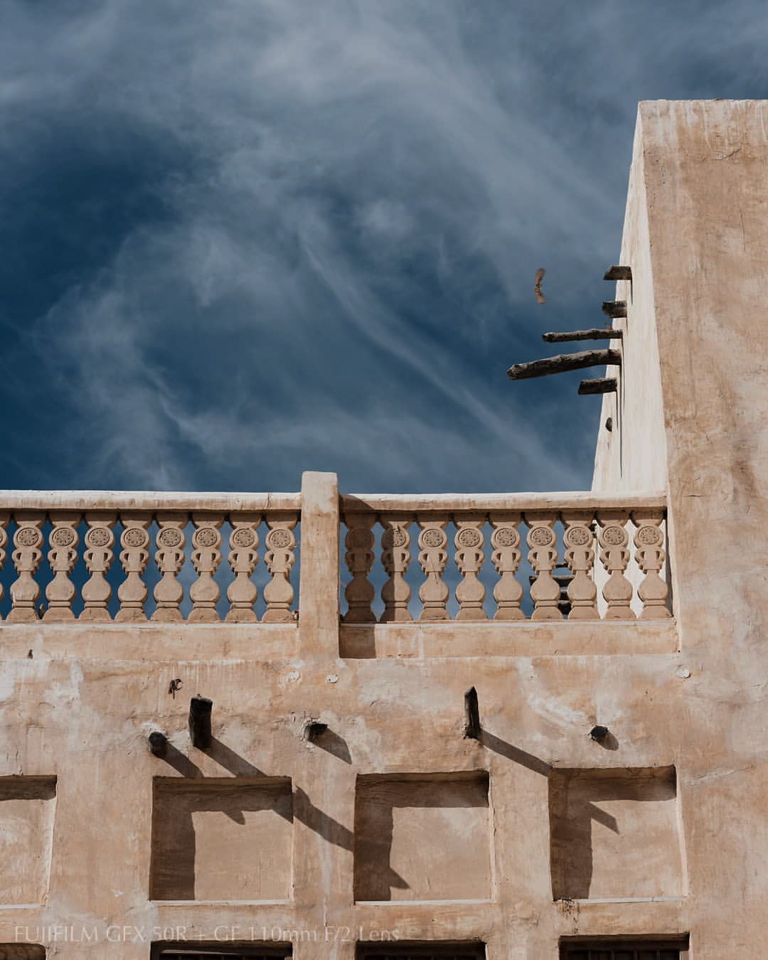 A carved balustrade of a traditional Kuwaiti building against the sky